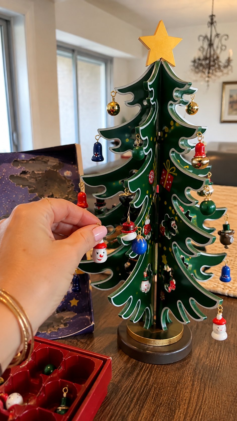 Vertical customer-style photo of a miniature ornament being hung on the wooden Christmas Advent tree